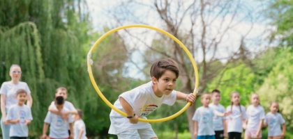 Kids enjoying a summer day playing with hula hoops in a park, showcasing friendship and fun.